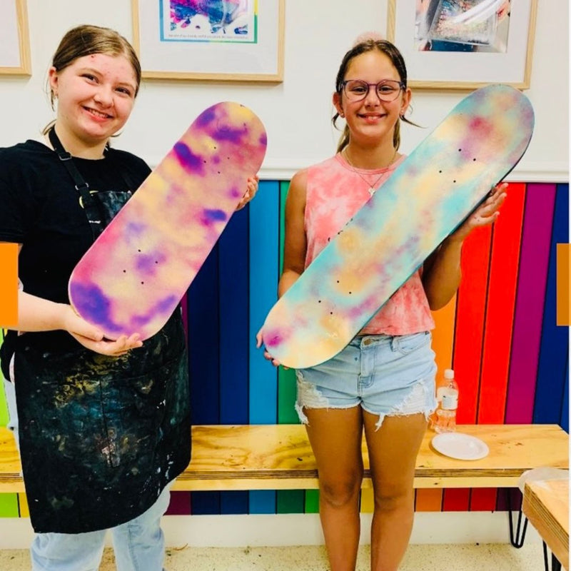 Two people holding tie-dye skateboards in DIY Invasion